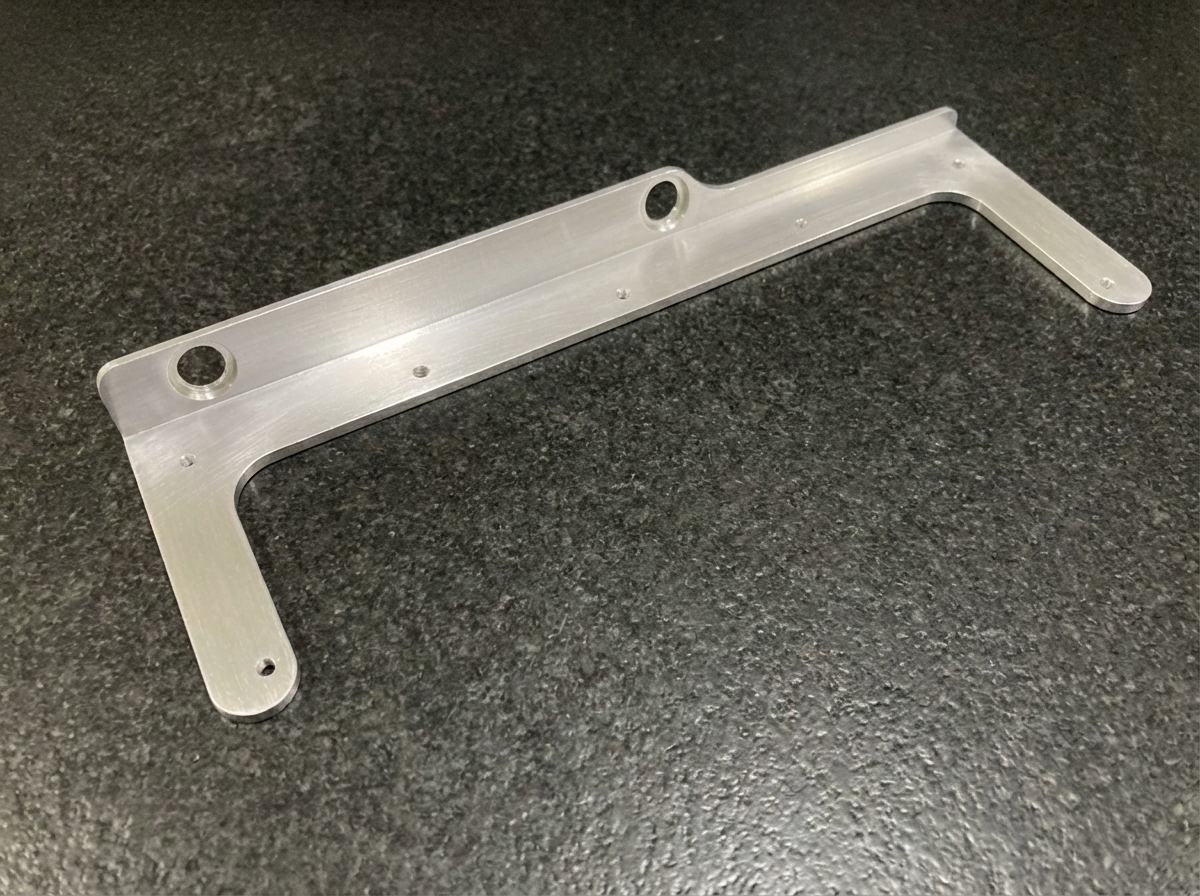 Custom-machined Aluminum bracket for mounting on a mill, securing a plexiglass shield to contain coolant and metal chips.